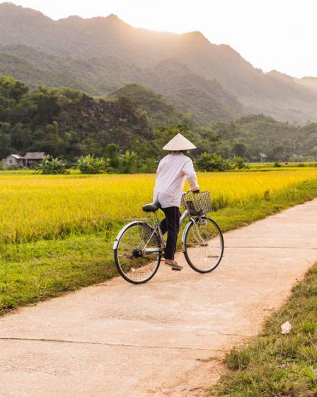 Photographie d'un homme en vélo dans les campagnes du Vietnam
